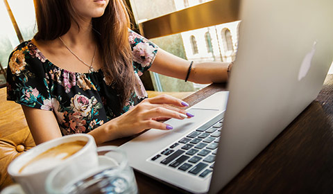 woman working on her computer with a cup of coffee by her side