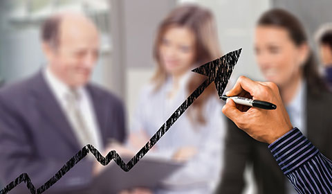 person drawing a line graph with business people in background