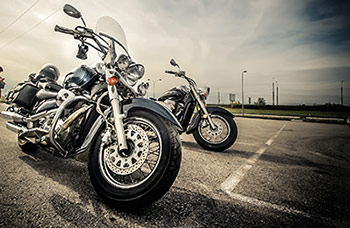 motorcycles parked side by side in parking lot